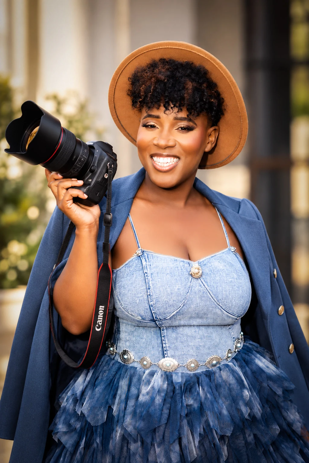 Chantelle Brown smiling in a hat and holding her camera